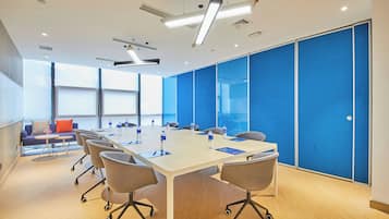 A conference room with a long table, chairs, and a blue partition wall.