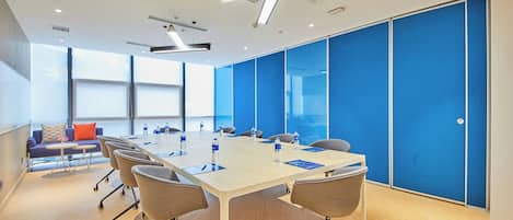 A conference room with a long table, chairs, and a blue partition wall.