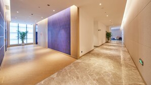 A modern interior with a long corridor, wooden flooring, and a mix of plain and patterned walls. - Holiday Inn Express Hangzhou Jiuzhou by IHG (Hangzhou)