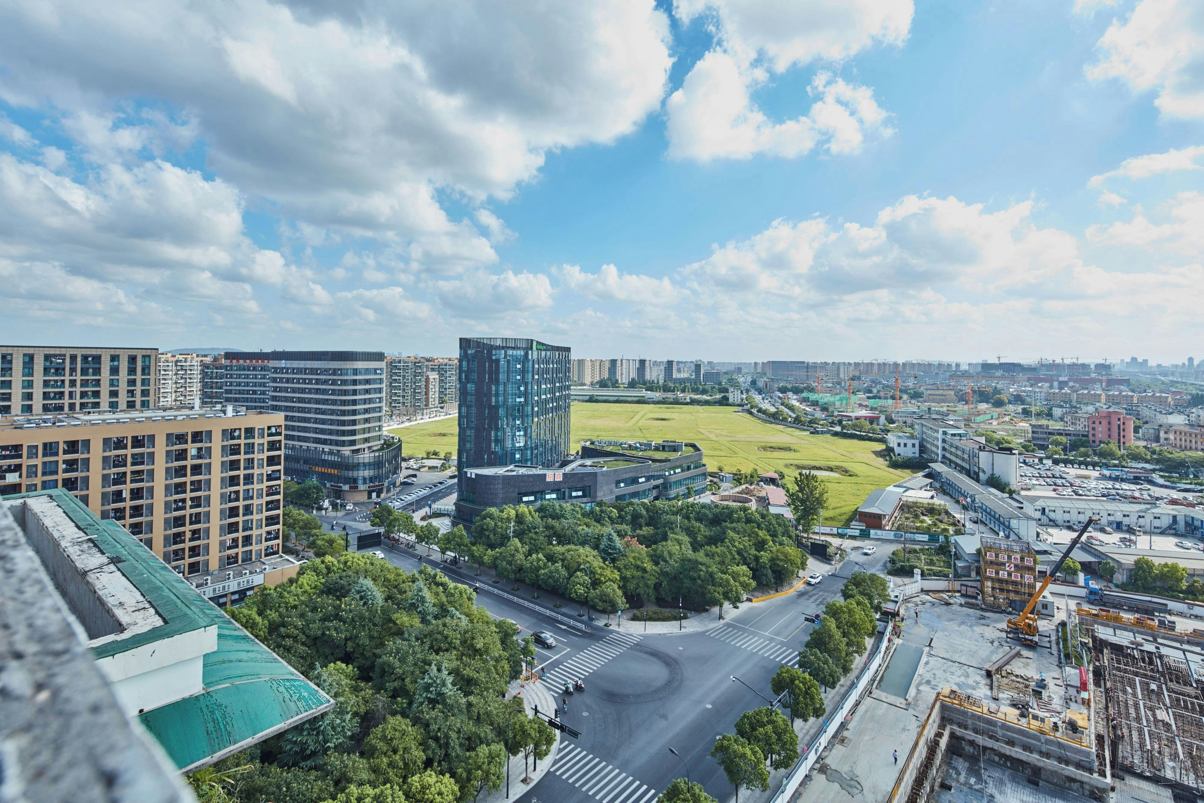 A cityscape with modern buildings, a large open field, and a busy intersection.