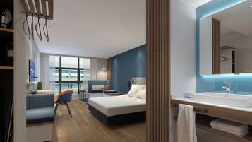 A modern hotel room with a bed, a desk, a chair, a large window, and a bathroom with a sink and mirror.