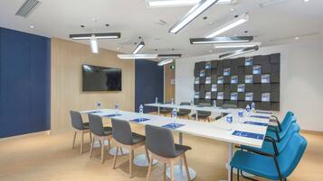 Un salón de conferencias con una larga mesa, sillas y un televisor de pantalla plana.