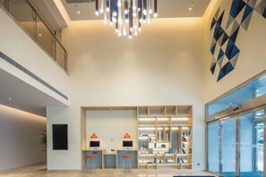 A modern interior with a high ceiling, a central chandelier, a bar area with stools, and a geometric wall art piece. - Holiday Inn Express Hangzhou Jiuzhou by IHG (Hangzhou)