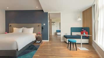 A modern hotel room with a large bed, a desk, and a seating area.