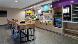 Un restaurante moderno con una barra alargada, zona de estar y un refrigerador lleno de bebidas.