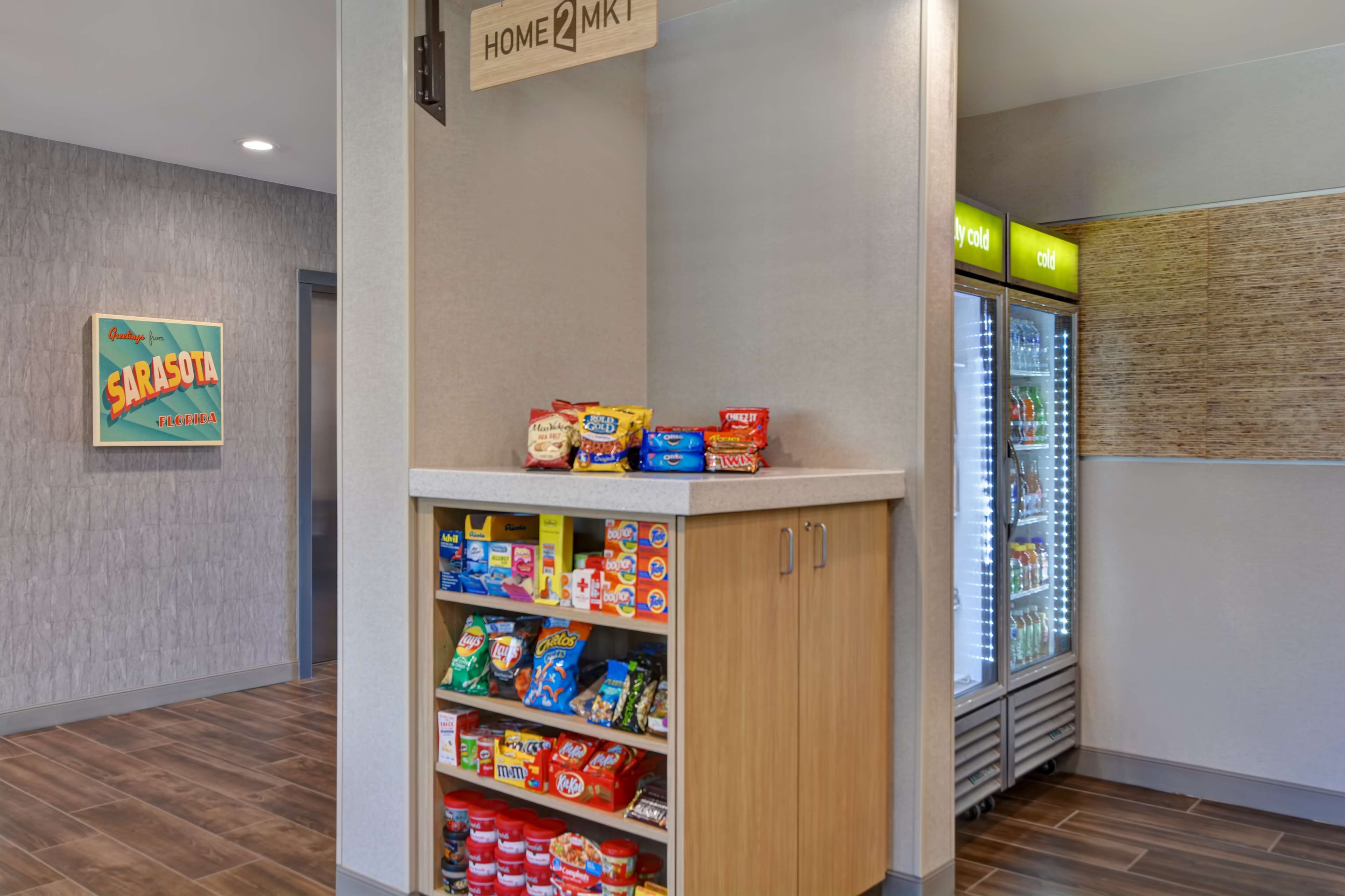 Un petit kiosque proposant divers aliments emballés et un réfrigérateur avec une étiquette indiquant « Froid ».