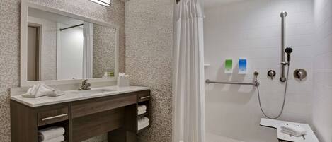 A modern bathroom with a shower, a vanity with a mirror, and a towel rack.