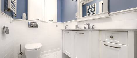 Un baño moderno con muebles blancos, inodoro blanco y pared de acento azul.