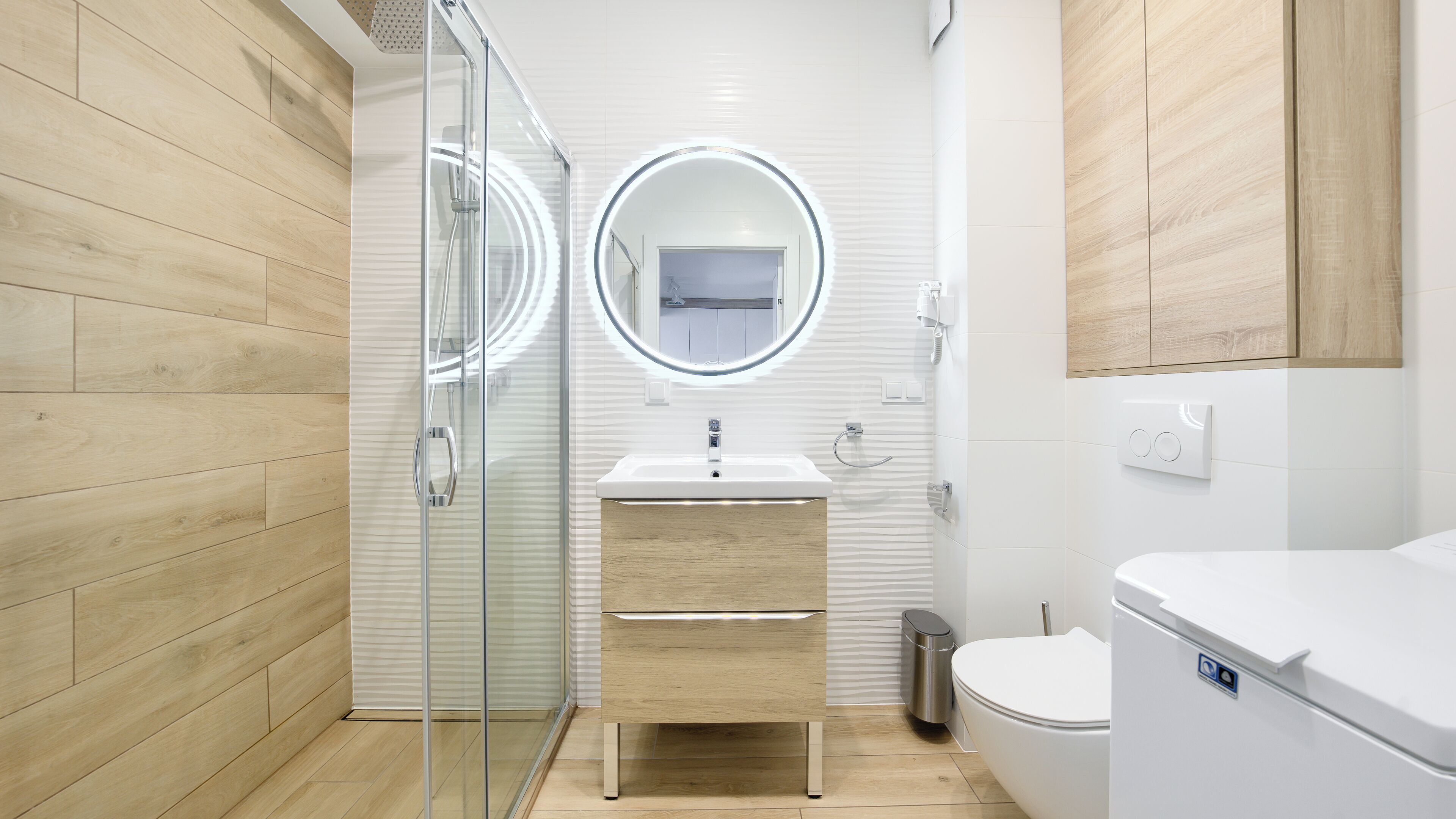 A modern bathroom with a glass shower enclosure, a white sink, and a toilet.