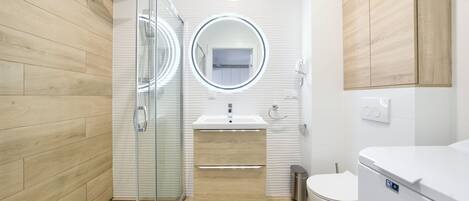 A modern bathroom with a glass shower enclosure, a white sink, and a toilet.