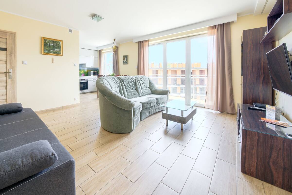 Ein modernes Wohnzimmer mit einem grauen Sofa, einem grünen Sessel und einem Glastisch.