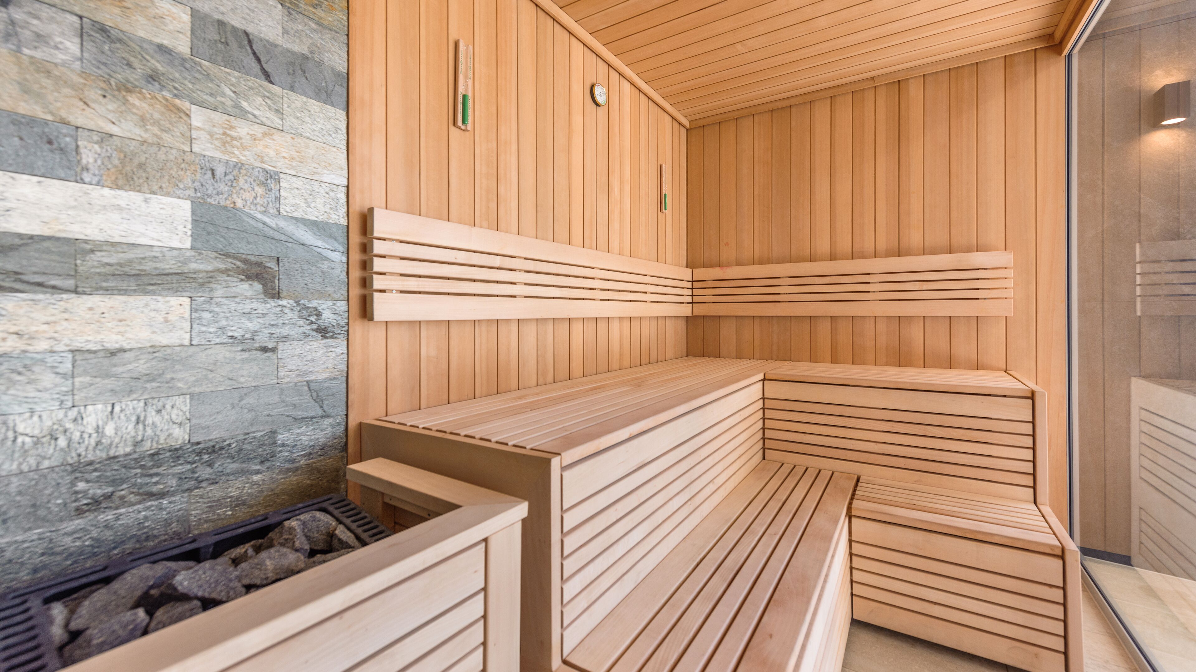 A sauna with wooden benches and a stone wall.