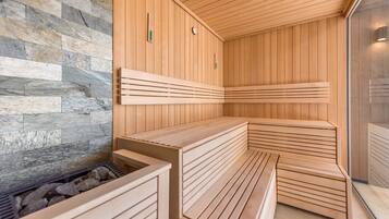 A sauna with wooden benches and a stone wall.