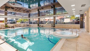 Ein Hallenbad mit einem Kind, Liegestühlen und einem Whirlpool.