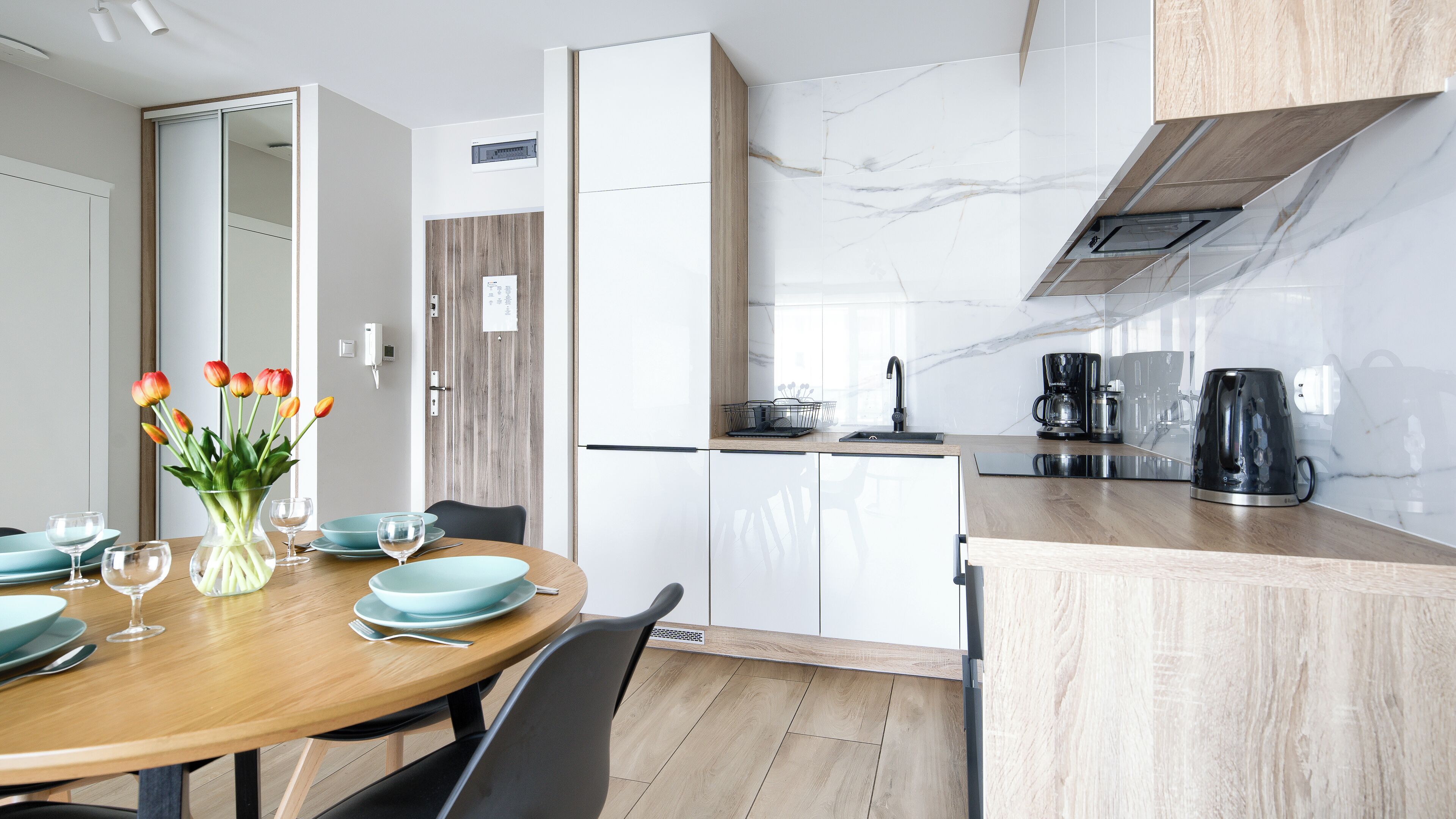 Une cuisine moderne avec des meubles blancs, un plan de travail en bois et une machine à café.