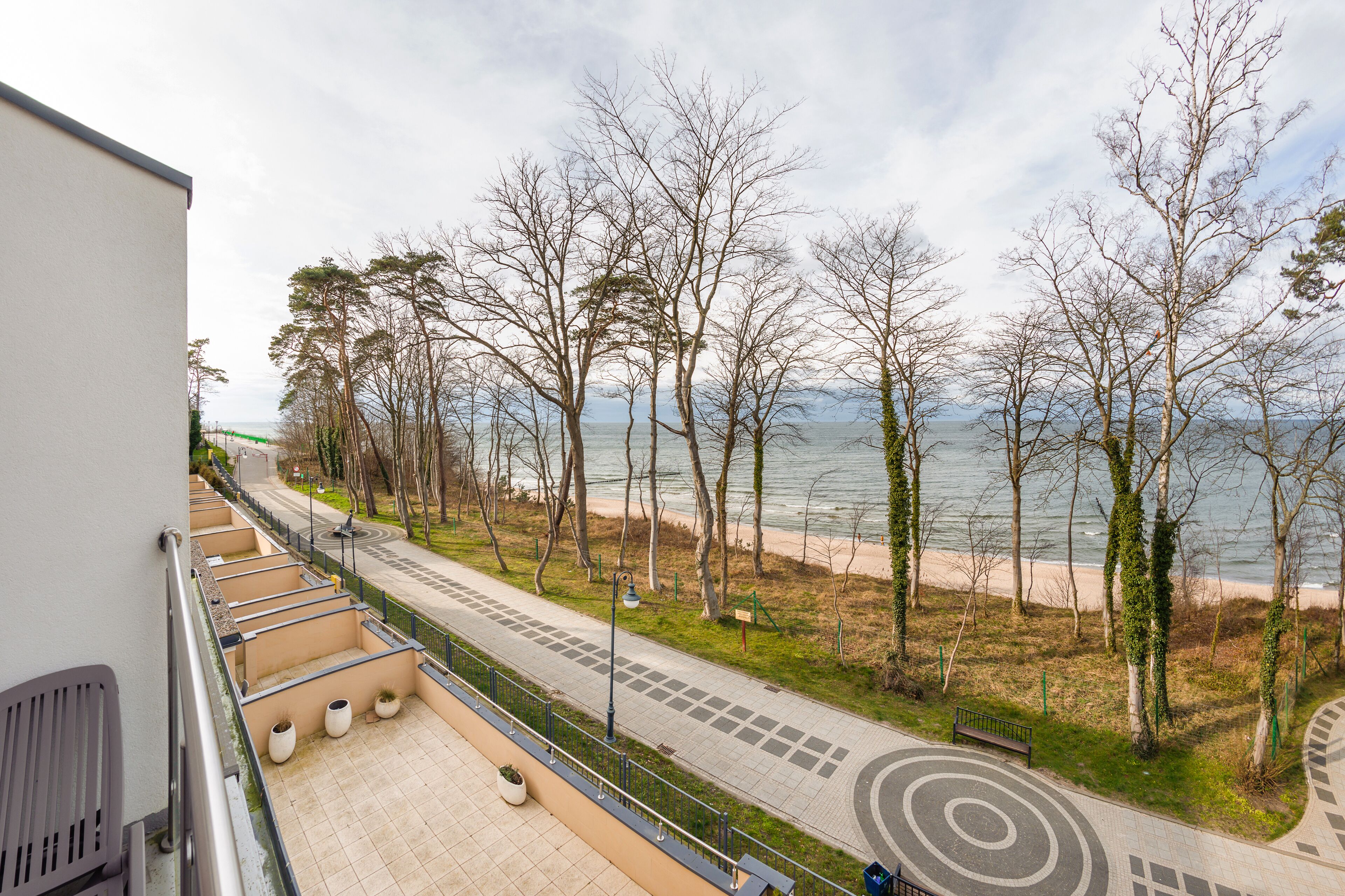 A balcony with a view of a beach and trees.