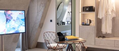 A modern room with a television, wicker chair, and a vanity with a mirror and shelves.