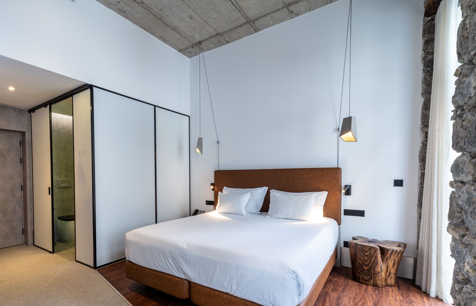 Un dormitorio moderno con una cama grande, un armario y una pared de piedra.