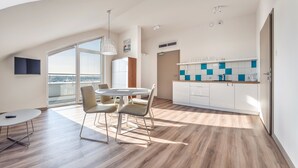 A modern kitchen with white cabinets, a blue and white tiled backsplash, and a dining area with a round table and chairs. - Apartamenty Sun & Snow Piec Morz (Ustronie Morskie)
