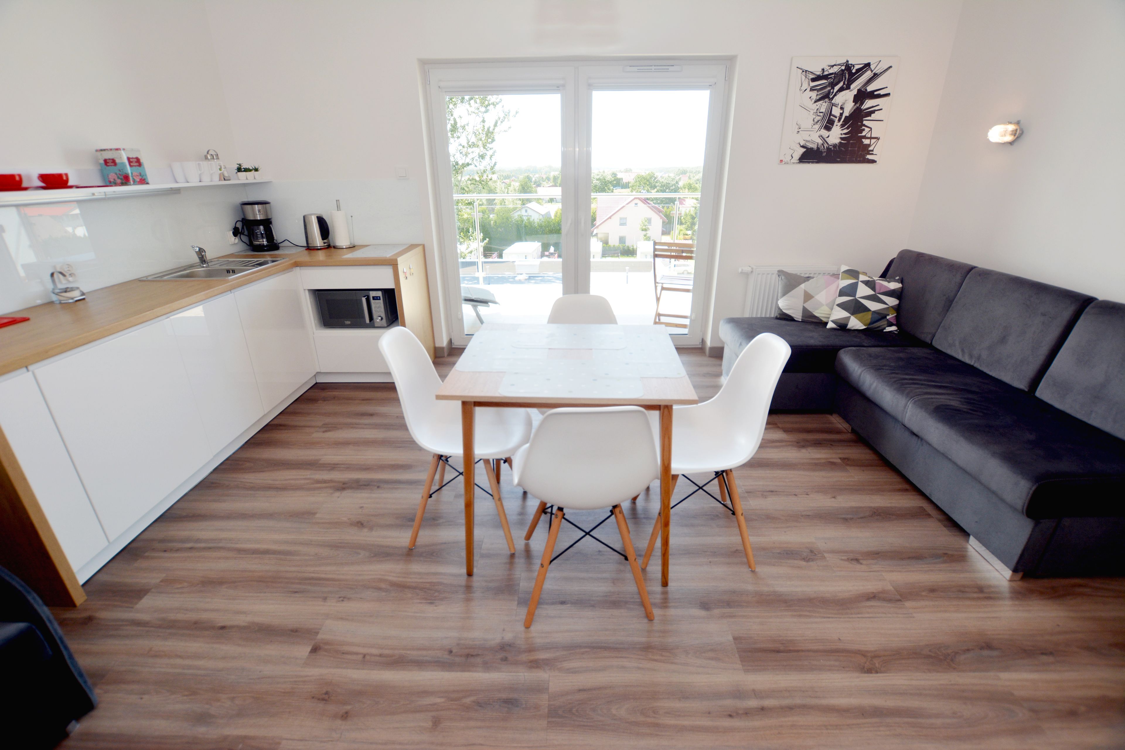 A modern kitchen with white cabinets, a wooden countertop, and a dining table with four chairs.