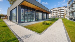 A modern building with large windows and a covered walkway. - Apartamenty Sun & Snow Piec Morz (Ustronie Morskie)