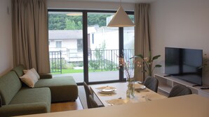 A modern living room with a sofa, dining table, and TV. - Hotel Gardinn - Free Parking and Quiet Garden (Bratislava)