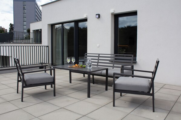 An outdoor patio with a table, two chairs, and a bench.
