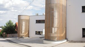 Two cylindrical structures with vertical slats, a paved area, and a building with windows and air conditioning units. - Hotel Gardinn - Free Parking and Quiet Garden (Bratislava)