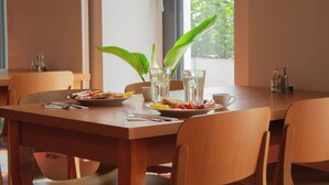 A dining table with chairs, plates of food, glasses, and a potted plant. - Hotel Gardinn - Free Parking and Quiet Garden (Bratislava)