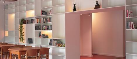 Een moderne bibliotheek met witte kasten, houten tafels en stoelen.