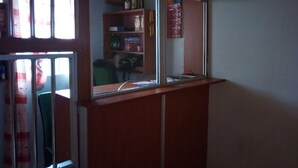 A room with a window, a desk, and a shelf with various items. - Kings Guest House (Kabati)