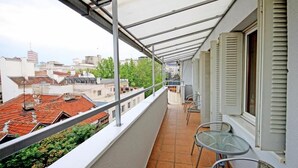 Un balcón con vistas a la ciudad, una mesa y dos sillas.