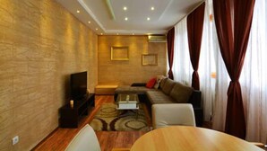 Una sala de estar moderna con una televisión de pantalla plana, un sofá, una mesa de centro y una mesa de comedor.