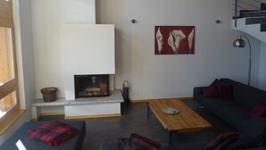 Una sala de estar moderna con chimenea, un sofá, una mesa de centro y un cuadro en la pared.