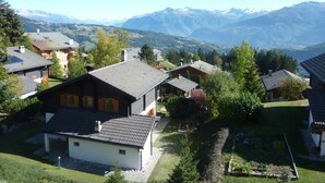 Vecindario residencial con casas, un jardín y montañas al fondo.