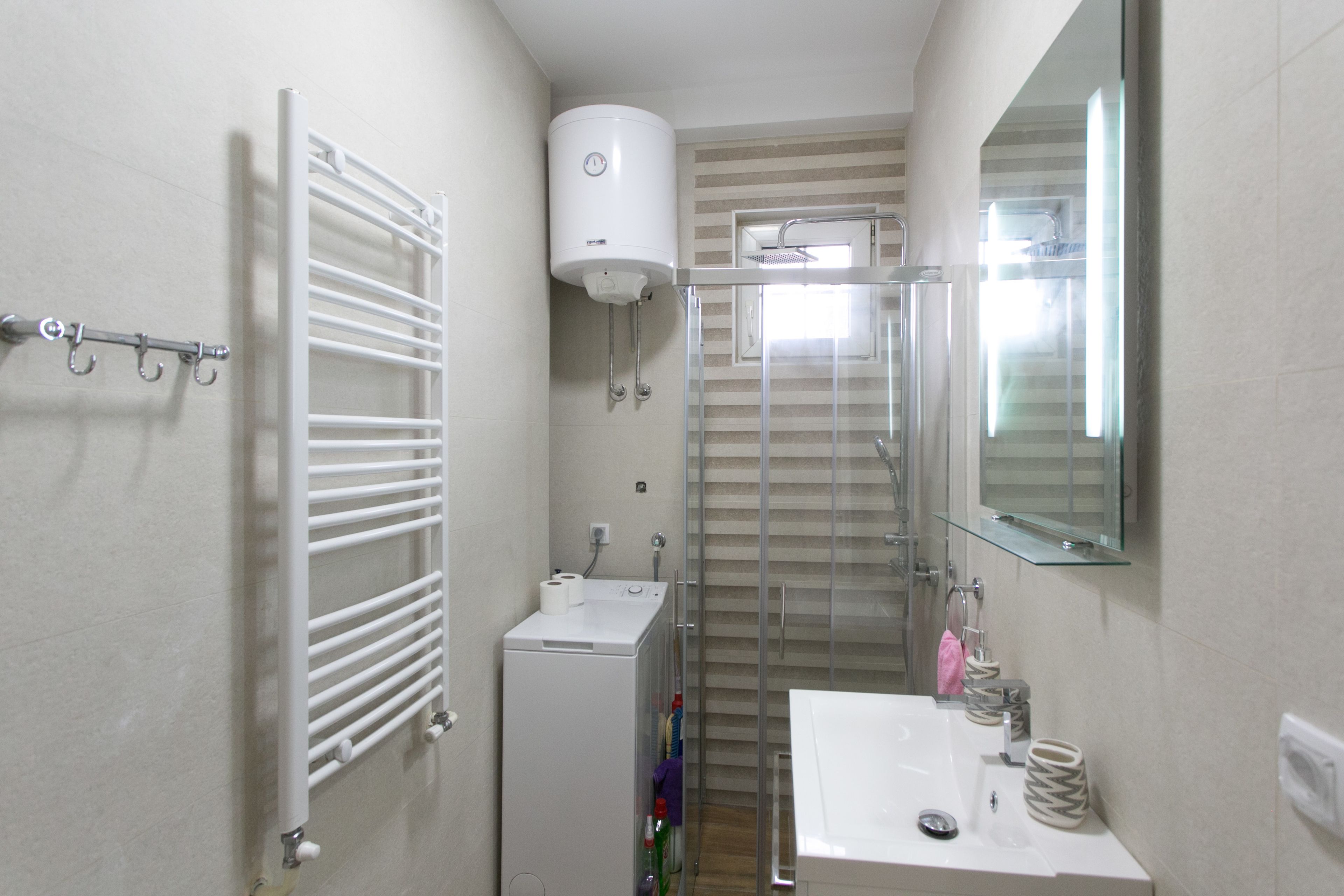 A compact bathroom with a glass shower enclosure, a white sink, and a towel rack.