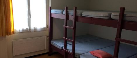Dormitorio con literas, ventana y cortinas.