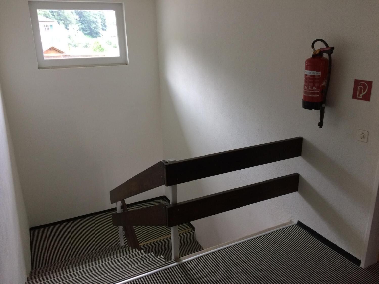 A staircase with a metal handrail and a fire extinguisher mounted on the wall.