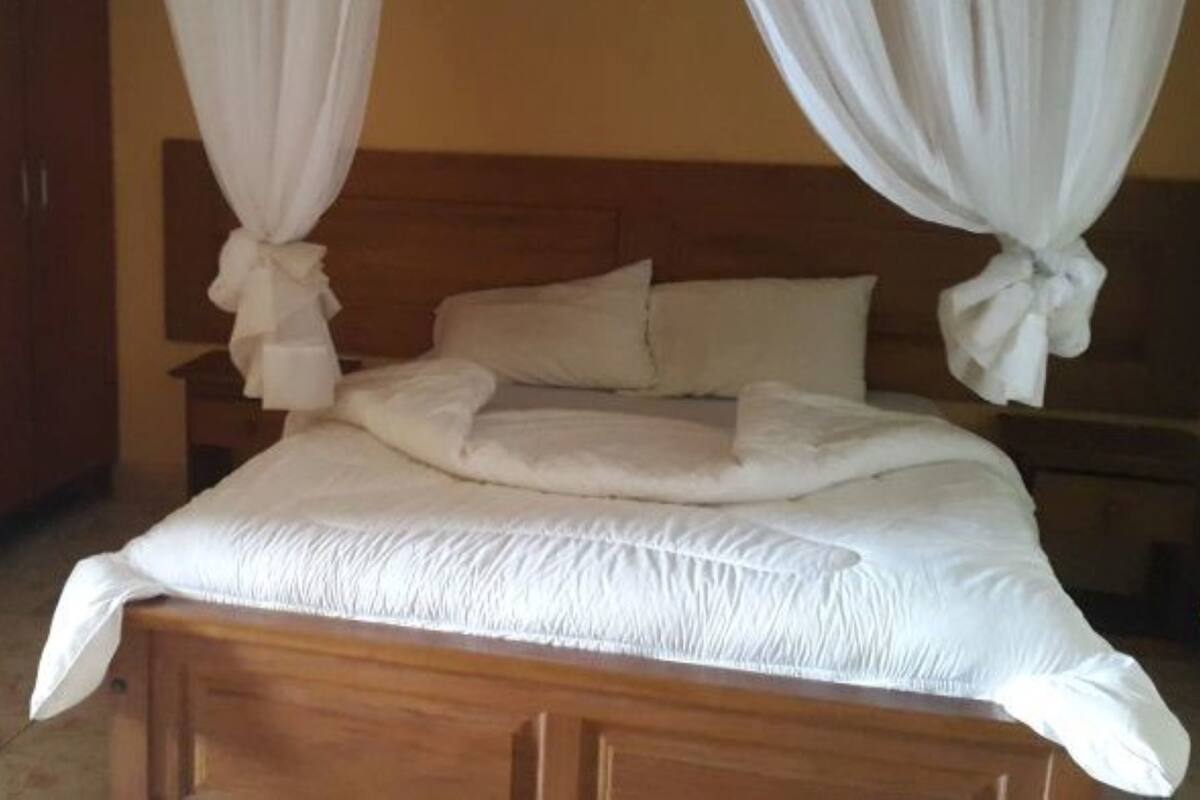 A neatly made bed with white bedding and a wooden headboard.