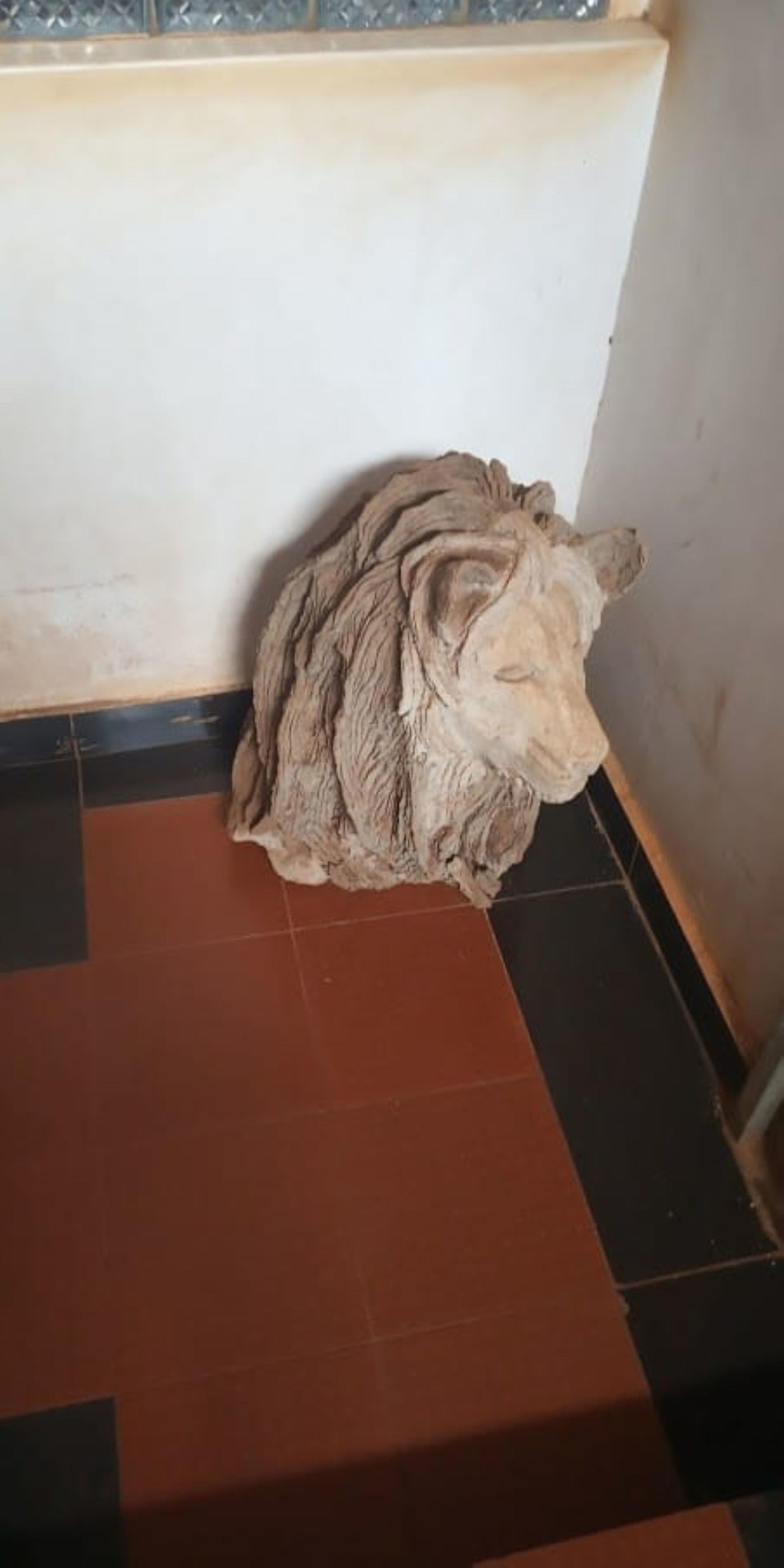 Una escultura de cabeza de león sobre un suelo de baldosas.