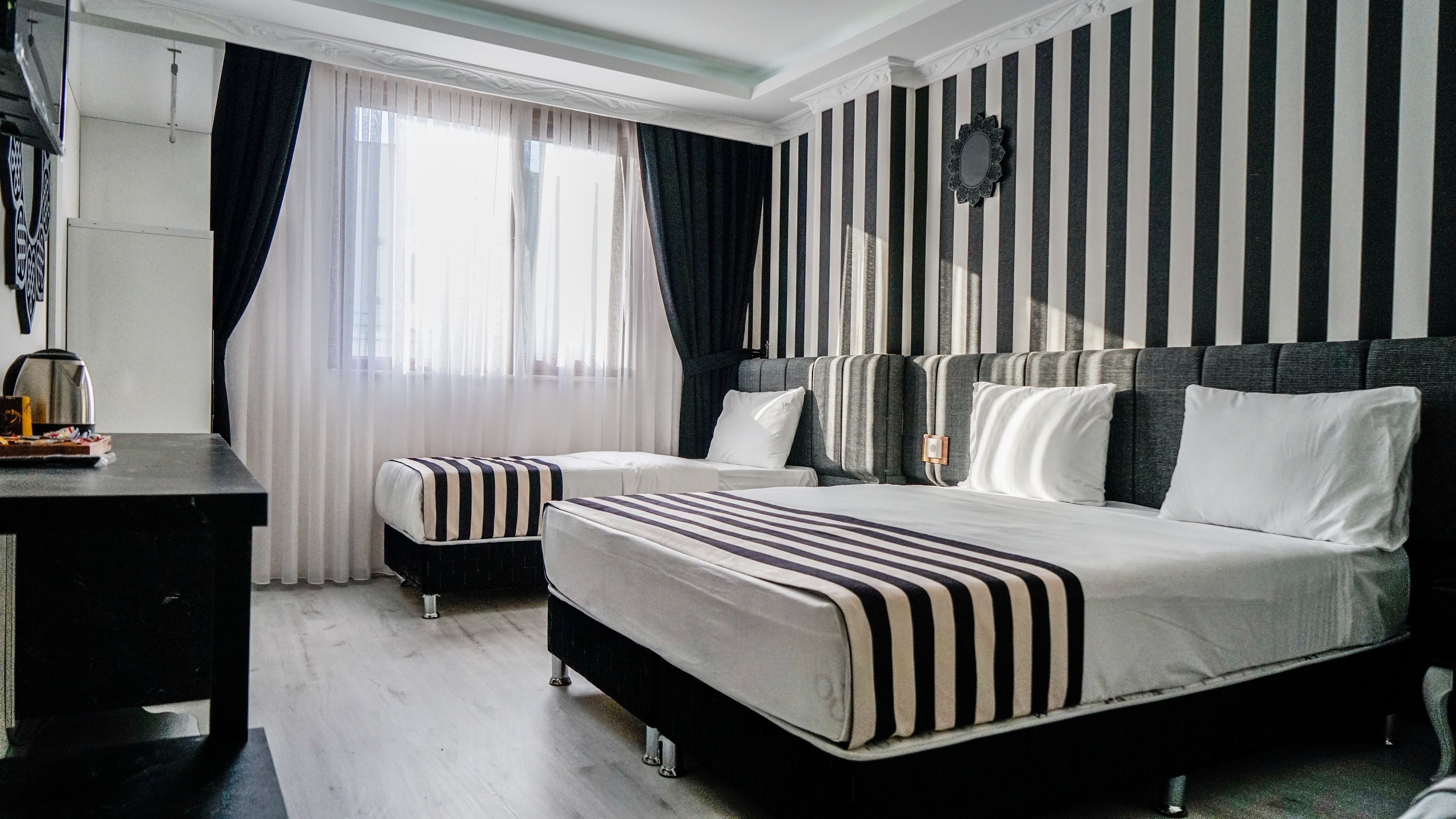 Une chambre d’hôtel avec un grand lit, deux tables de chevet, un bureau et une fenêtre avec des rideaux.