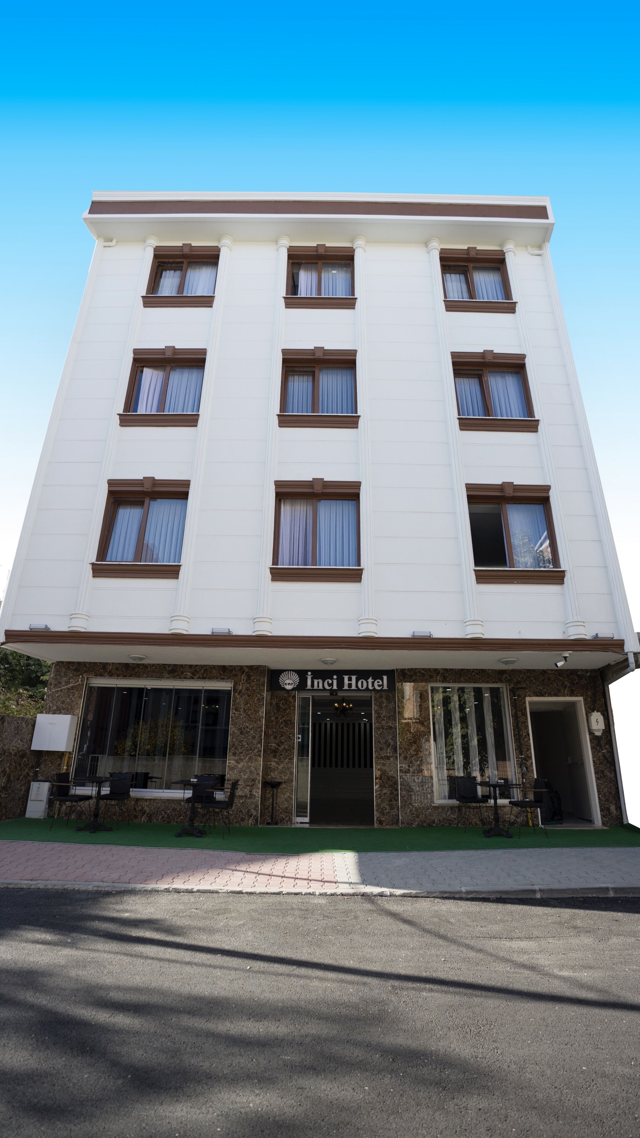 A multi-story hotel with a white facade, multiple windows with brown frames, and a sign reading "Inci Hotel".