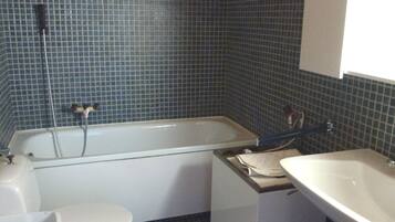 A bathroom with a bathtub, toilet, and sink.