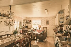 A cozy kitchen with wooden cabinets, a chandelier, and a dining area with a table and chairs. - Farmlodge (Brastad)