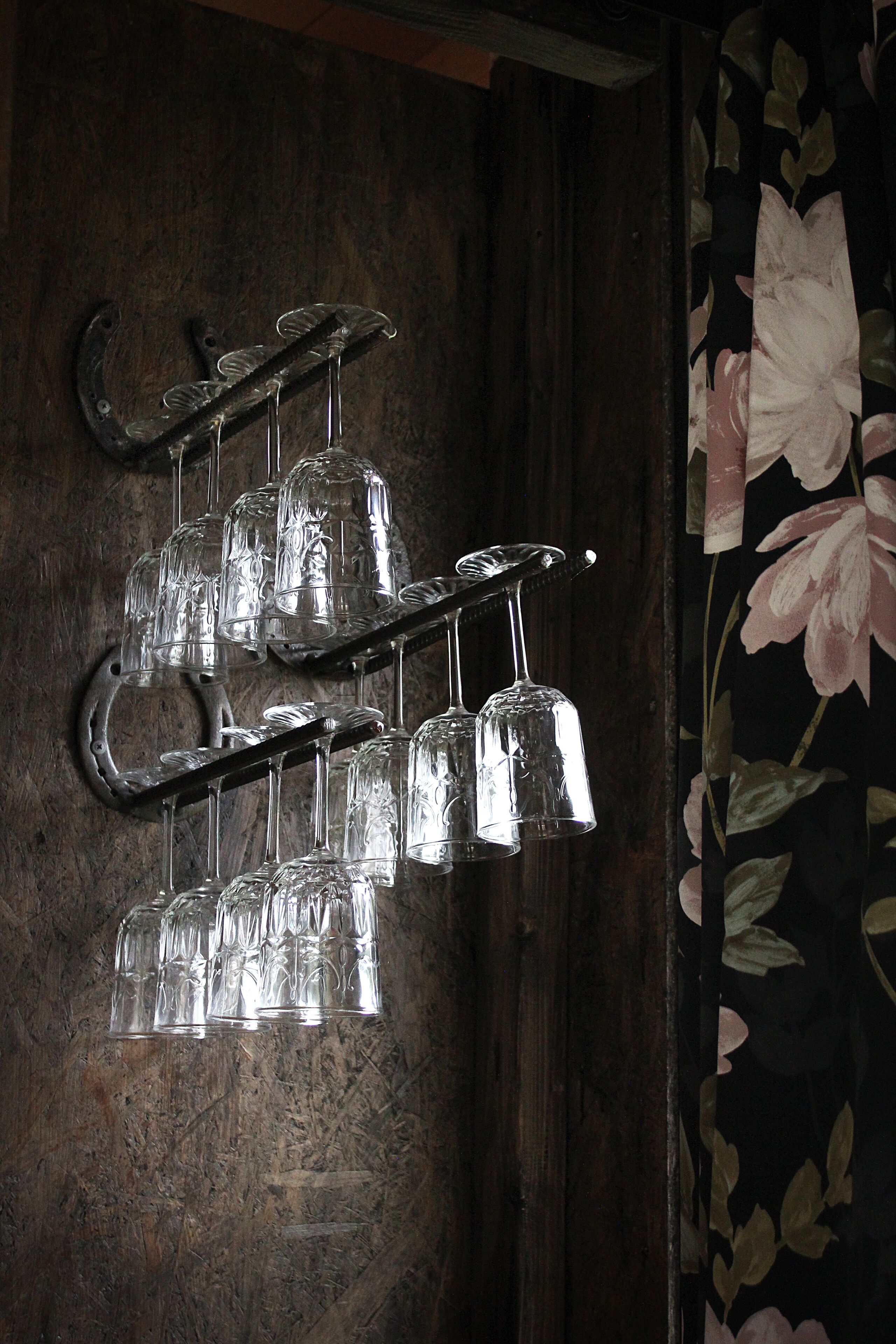 A wall-mounted glassware rack with multiple tiers holding several glasses.
