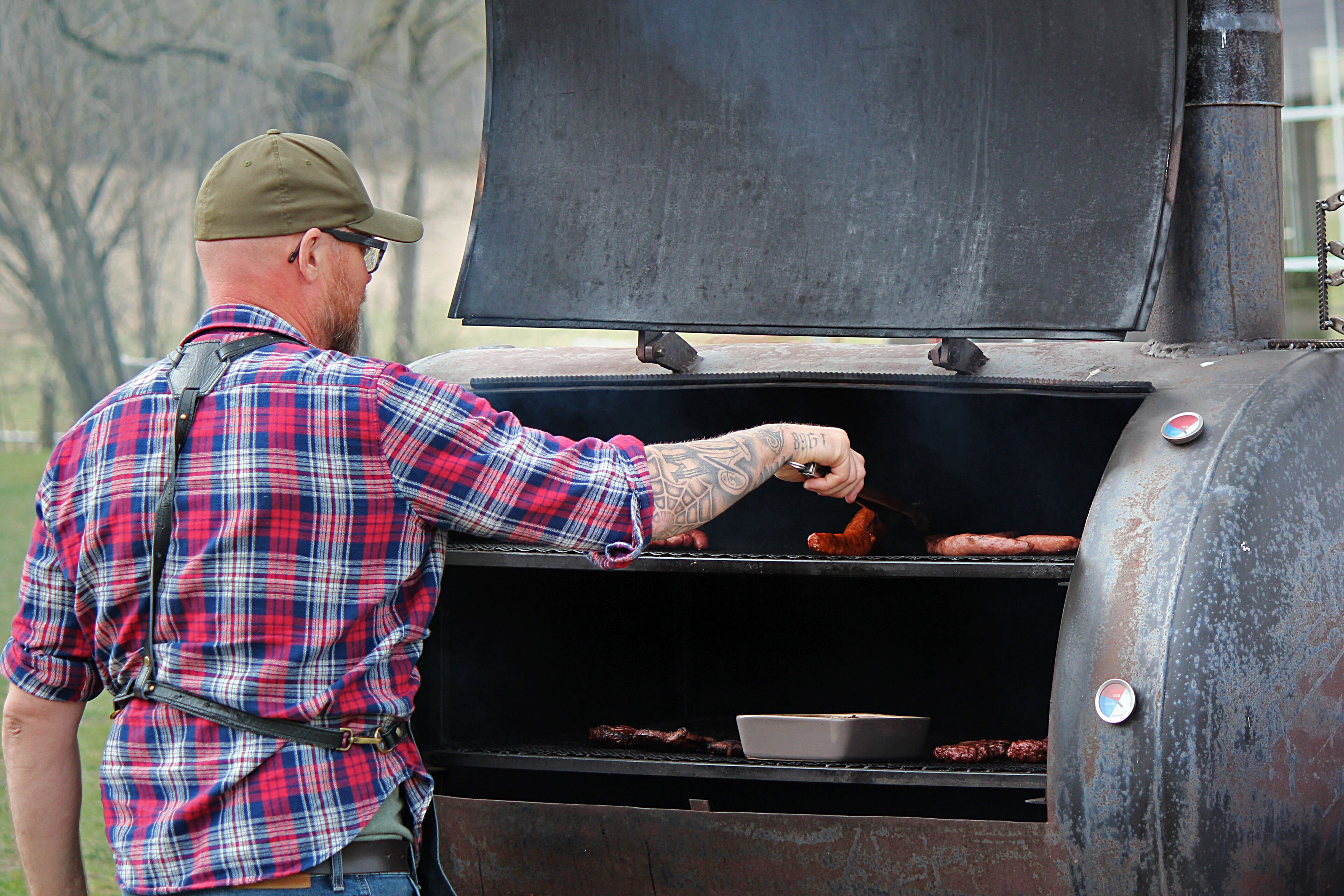 A man grilling sausages on an outdoor grill.