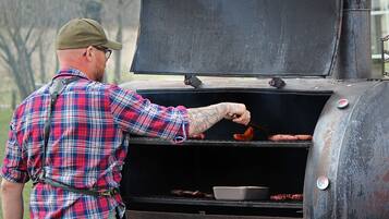 A man grilling sausages on an outdoor grill.