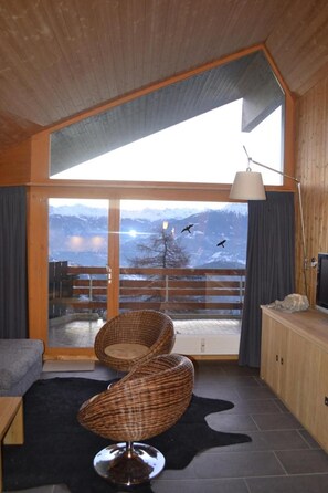 A room with a large sliding glass door leading to a balcony with a mountain view. - Appartement Cristal 512 (Ayent)