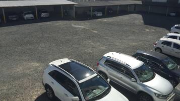 Un estacionamiento con varios coches, incluyendo vehículos SUV blancos y plateados, y un edificio de techo plano al fondo.