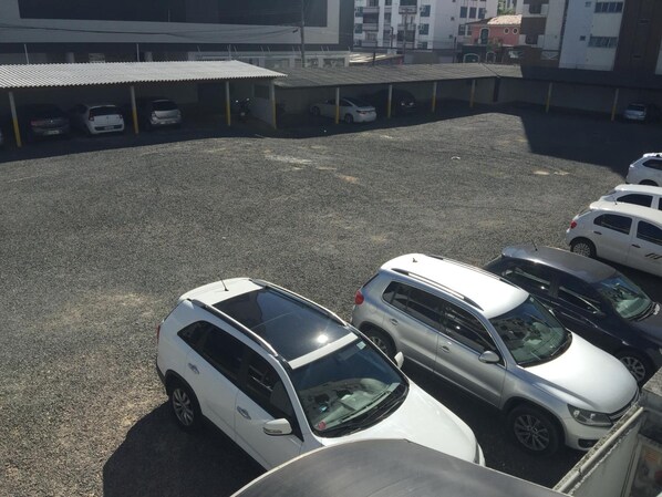 Un estacionamiento con varios coches, incluyendo vehículos SUV blancos y plateados, y un edificio de techo plano al fondo.